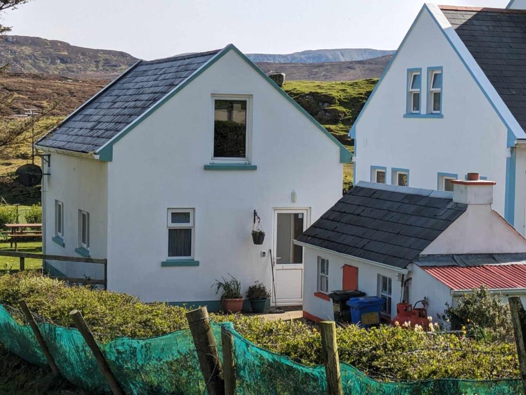 una casa blanca con una valla delante en An Teach Beag Glencolmcille, little home from home, en Glencolumbkille