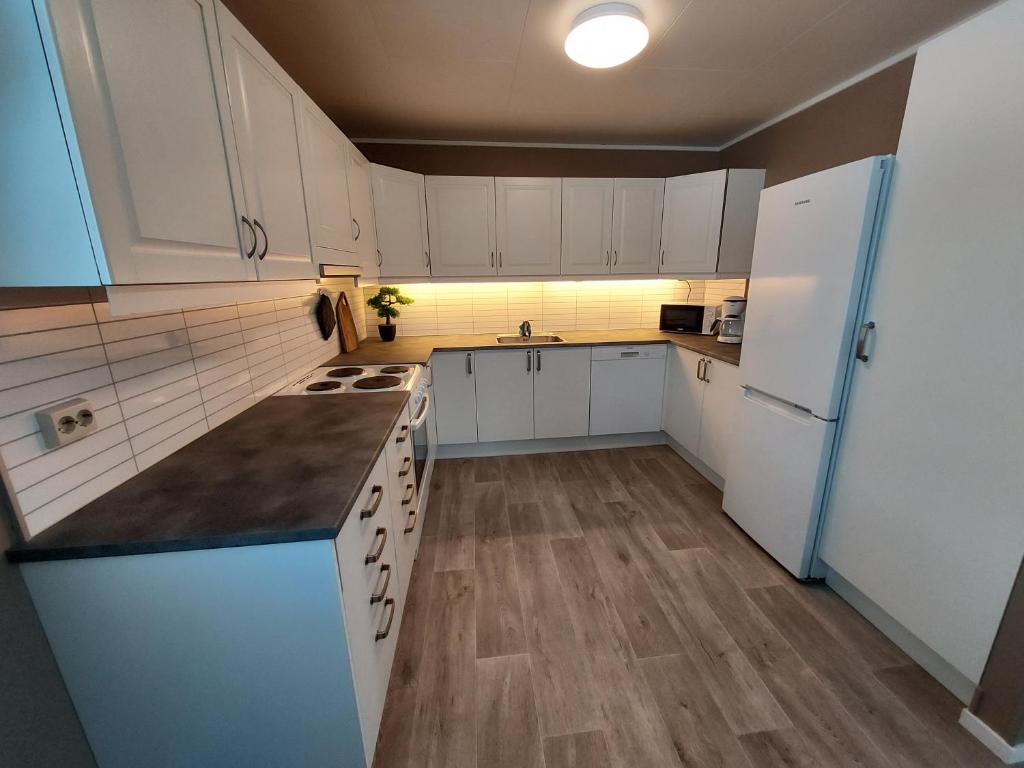 a kitchen with white cabinets and a white refrigerator at Sentrumsnær overnatting in Alta