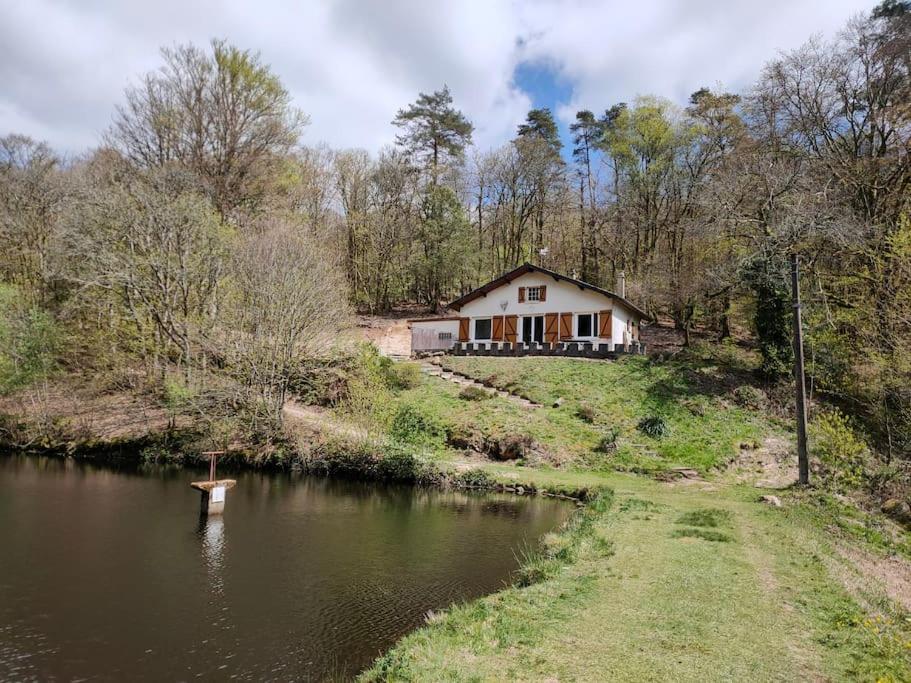 a house on a hill next to a river at A l' orée des bois, maison avec étang in Saint-Sylvestre