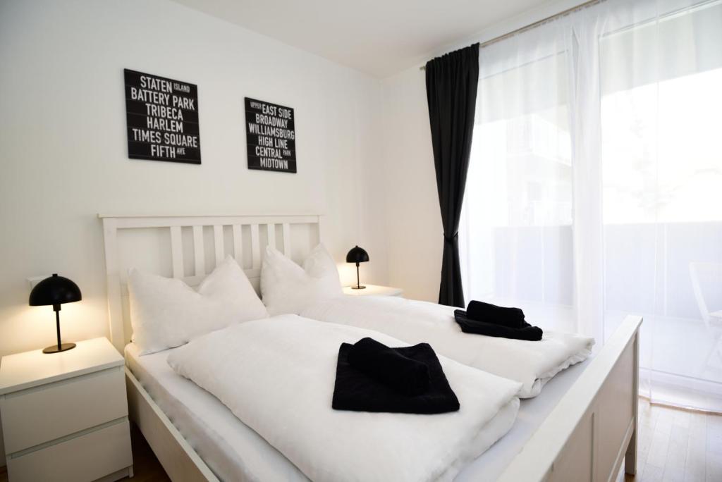 - une chambre avec un lit blanc et 2 oreillers noirs dans l'établissement Flataid Apartments Stadion & Messe Graz, à Graz