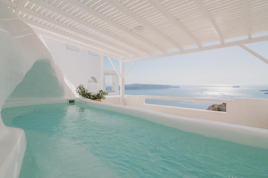 una piscina en un edificio blanco con agua azul en Apeiron Blue Santorini - Sustainable Adults Only 14 Plus en Fira