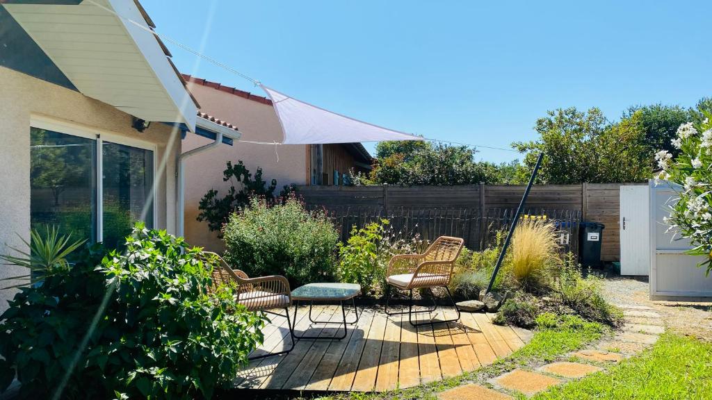 un patio avec des chaises, une table et un parasol dans l'établissement Maison de vacances Arès, Bassin d'Arcachon, à Arès