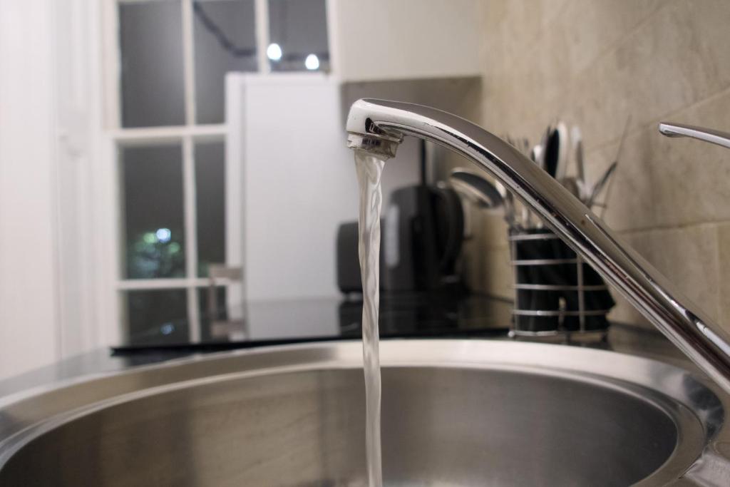 a kitchen sink with water running from a faucet at 1 bedroom apartment - The Onyx in Cheltenham