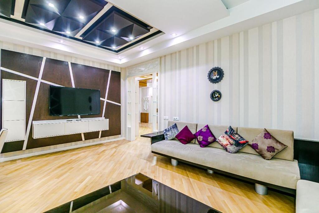 uma sala de estar com um sofá e uma televisão de ecrã plano em Konsul Apartment Nizami em Baku