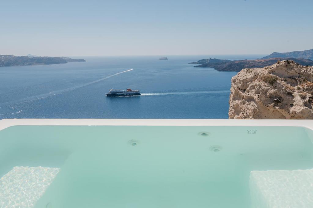 una barca in un grande bacino d'acqua di Apeiron Blue Santorini - Sustainable Adults Only 14 Plus a Firà