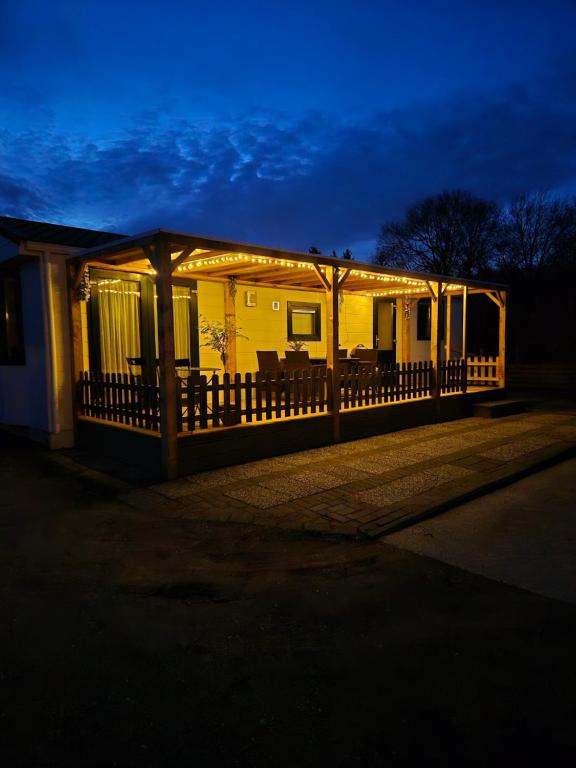 una casa con un porche con luces encendidas por la noche en vakantiehuisje Holterberg, en Holten