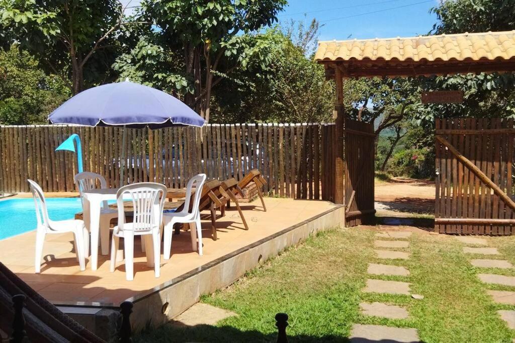 eine Terrasse mit einem Tisch, Stühlen und einem Sonnenschirm in der Unterkunft Casa das orquídeas in Santana do Riacho