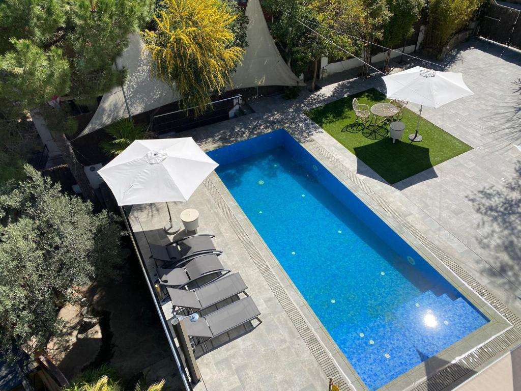 een uitzicht over een zwembad met stoelen en parasols bij Costa Maresme Barcelona , Garden Guest House,Relax & Pool in Cabrils