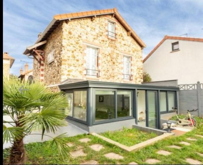 a house with large glass windows and a palm tree at Élégant Appartement Calme et Spacieux avec Jardin in Choisy-le-Roi