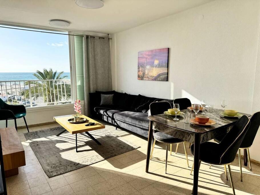 een woonkamer met een tafel en een bank bij Sea Breeze Apartment in Qiryat Yam