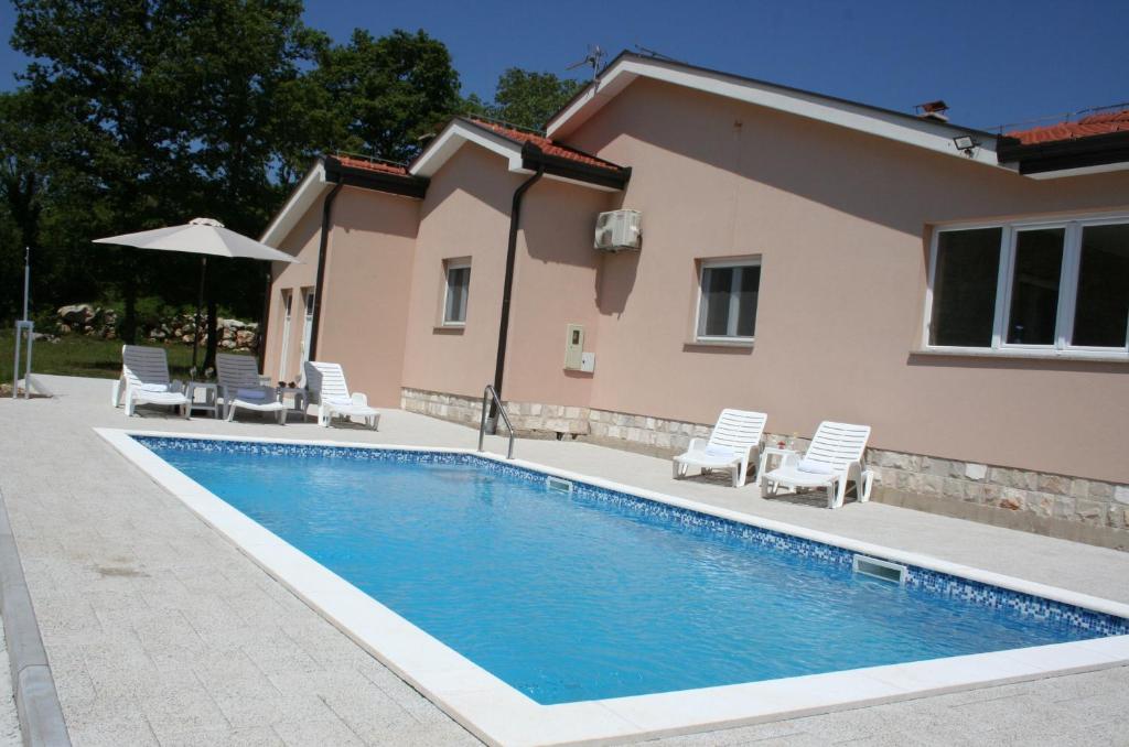 uma piscina com cadeiras e uma casa em Villa GLAM em Ljubuski