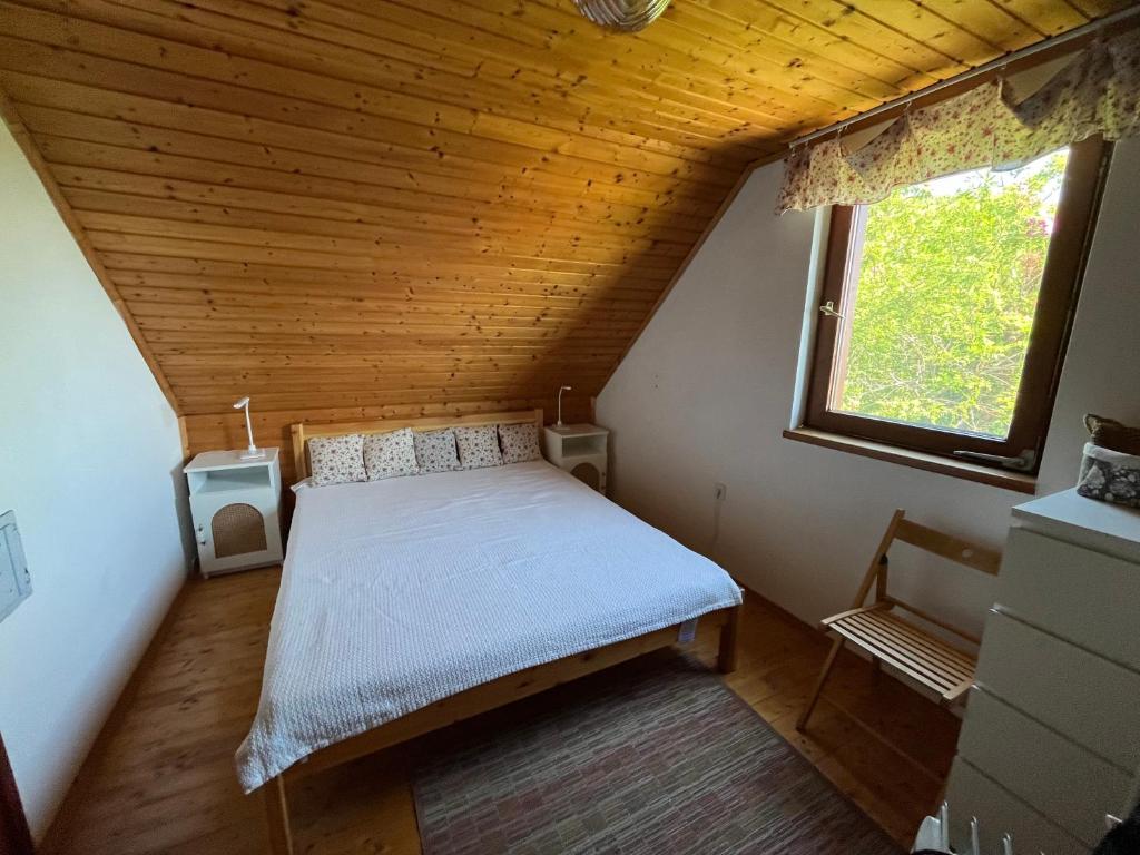 een slaapkamer met een bed in een kamer met een raam bij Ágnes Panoráma Háza in Révfülöp