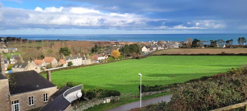 a large green field in a small town with the ocean at Gite du Palis - maison vue mer in Omonville-la-Rogue