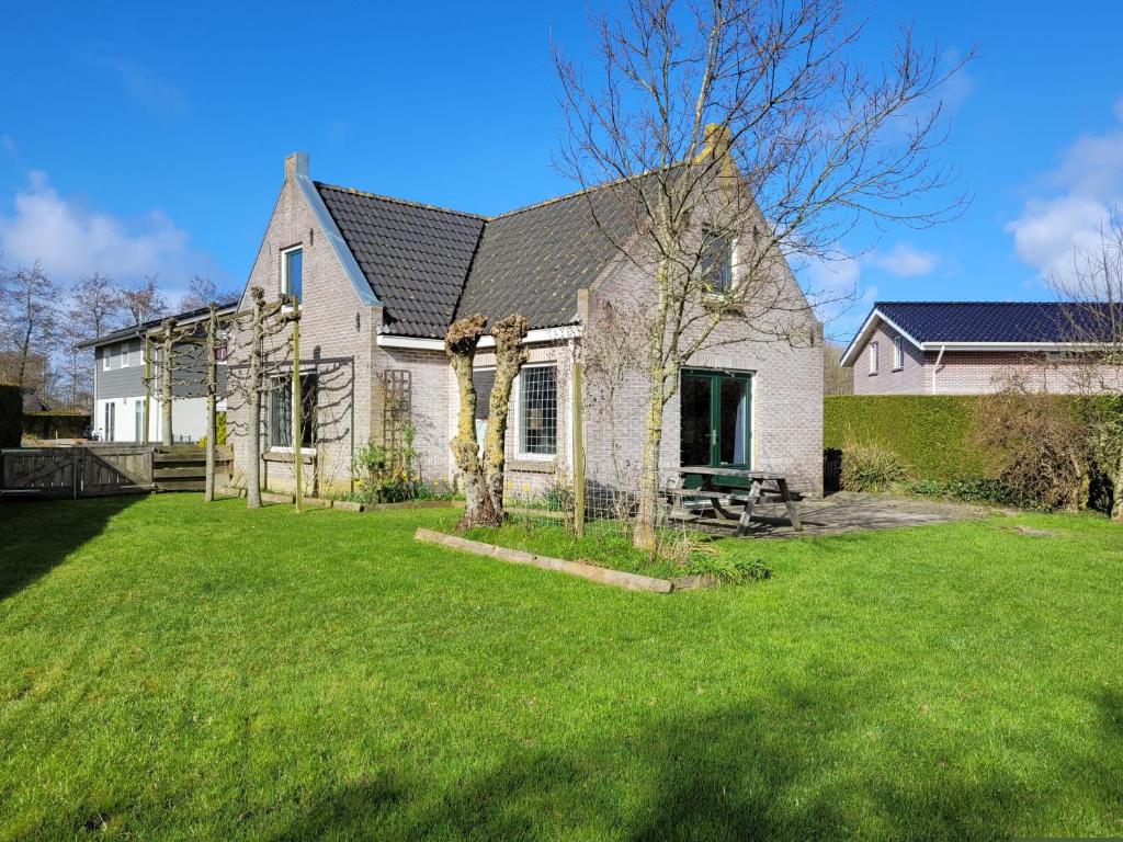 une grande maison blanche avec une cour gazonnée dans l'établissement Holiday Home Friesland near the Wadden Sea with Wifi and 3 Bedrooms, à Tzummarum
