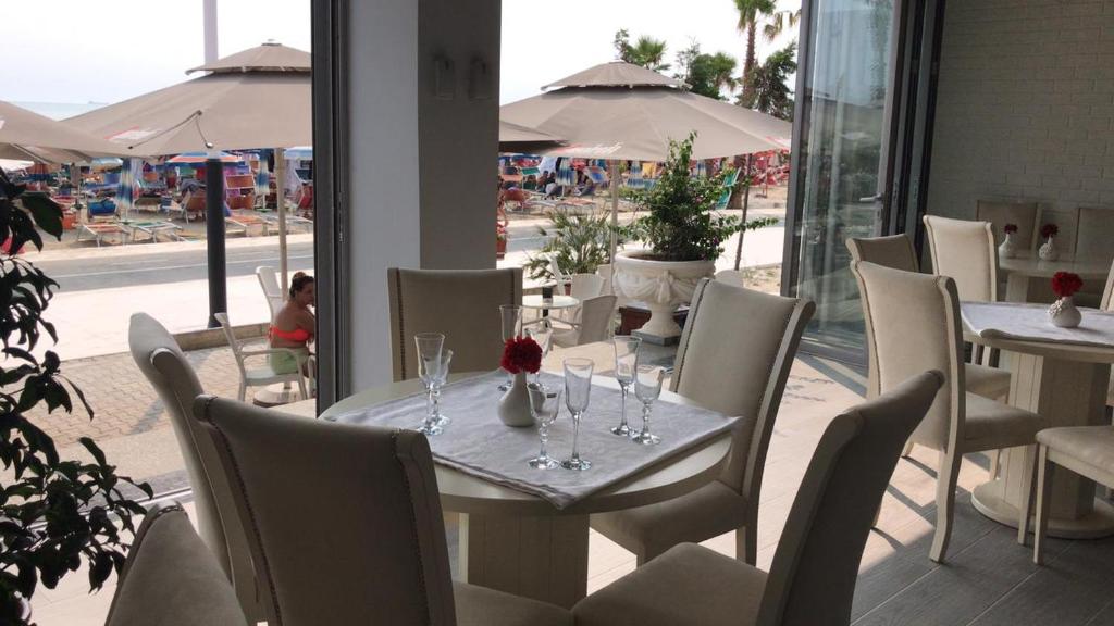 una mesa con copas de vino y una flor en ella en DIELL HOTEL, en Durrës