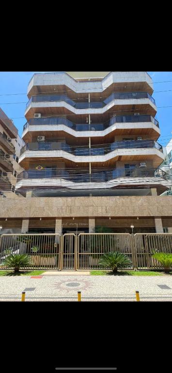 un grand bâtiment avec une clôture devant lui dans l'établissement Alugo apartamento de luxo, 3 quartos, 2 vagas, à Cabo Frio
