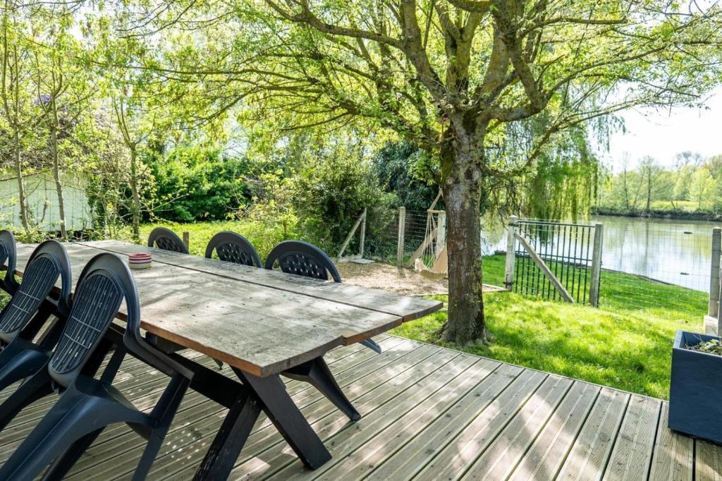 une table et des chaises en bois sur une terrasse à côté d'un arbre dans l'établissement Maison au bord du Loir, à La Flèche