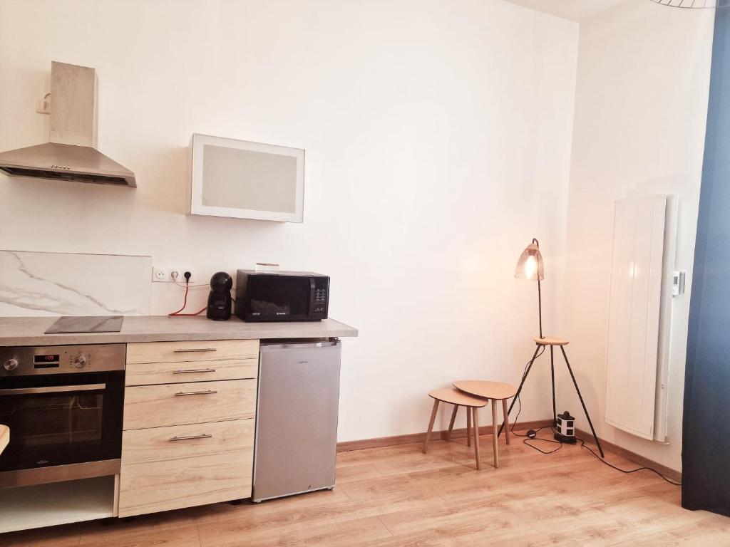 a kitchen with a stainless steel refrigerator and a table at appartement cosy en centre ville avec terrasse in Villefranche-sur-Saône