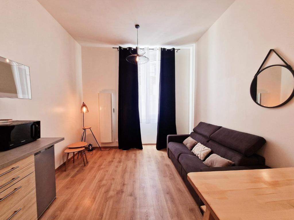 a living room with a couch and a table at appartement cosy en centre ville avec terrasse in Villefranche-sur-Saône