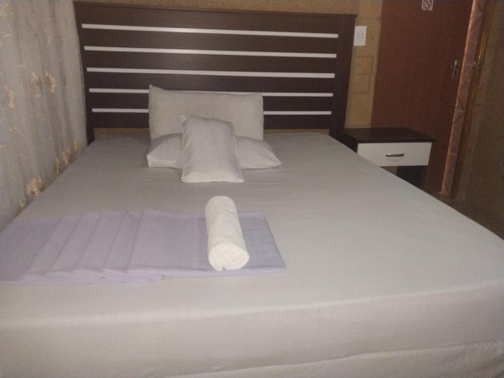 Una cama con dos rollos de toallas blancas. en M-Dee Guest Pass Lodge, en Phuthaditjhaba