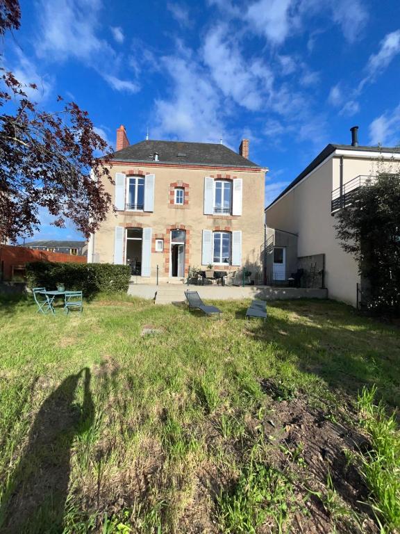 une grande maison sur un terrain herbeux à côté d'un bâtiment dans l'établissement Maison Coeur centre ville Arnage 24h du Mans, à Arnage