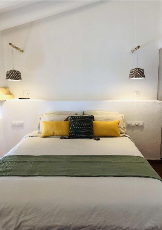 ein Schlafzimmer mit einem großen Bett mit gelben Kissen in der Unterkunft MAISON HÔTEL SES PENYES in Alaior