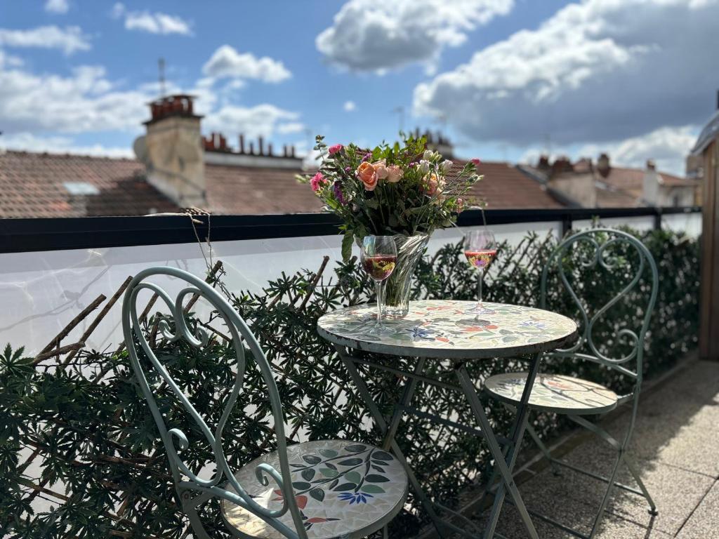 d'une table, de chaises et d'un vase de fleurs sur le balcon. dans l'établissement 15min From Paris Center - Bright Large Top Floor - 4BD, à Asnières-sur-Seine