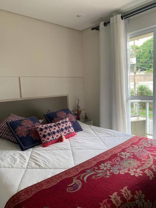 łóżko z 2 poduszkami i oknem w obiekcie Sobrado Charmoso e Aconchegante / Santa Felicidade PR w mieście Kurytyba