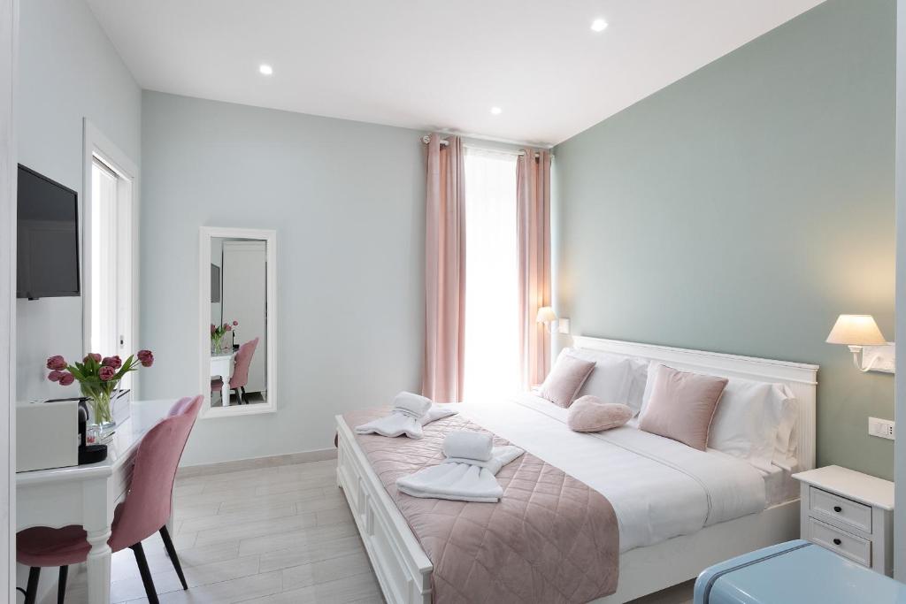 a white bedroom with a large bed and a desk at Colosseo House in Rome
