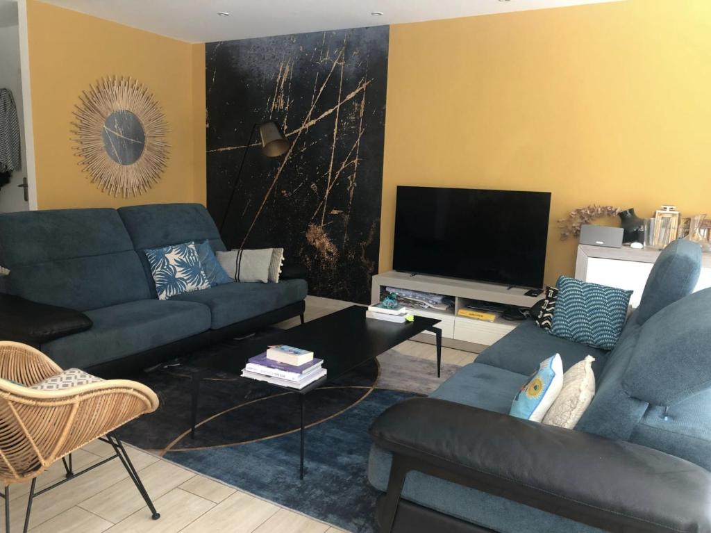 un salon avec des canapés bleus et une télévision dans l'établissement Charmant appartement avec jardin à 10 mn du Palais, à Cannes