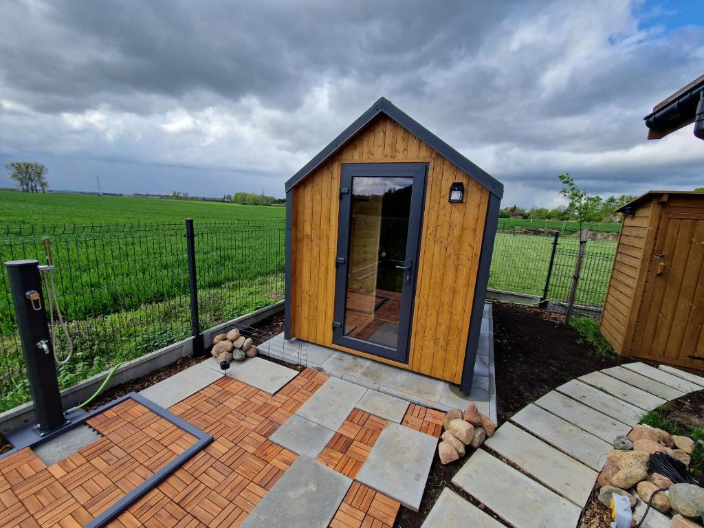 ein kleines Holzhaus mit einem Zaun auf einem Feld in der Unterkunft Pole biwakowe U Marcina in Kwidzyn