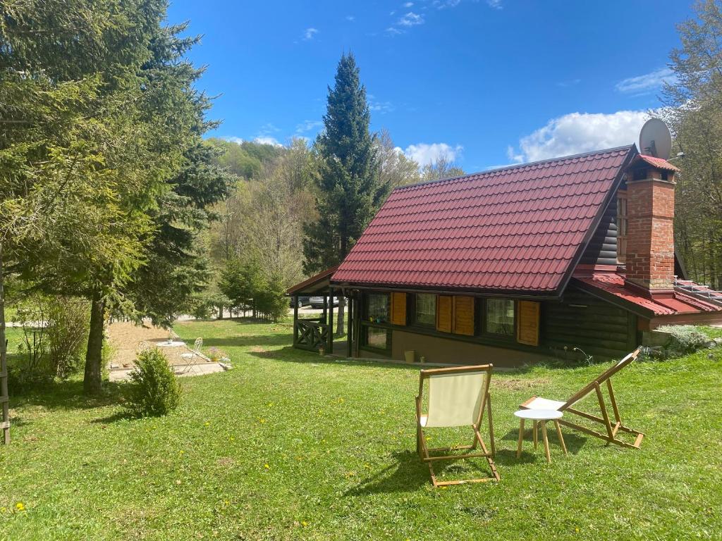 ein Haus mit zwei Stühlen davor in der Unterkunft Puhova Koliba in Delnice