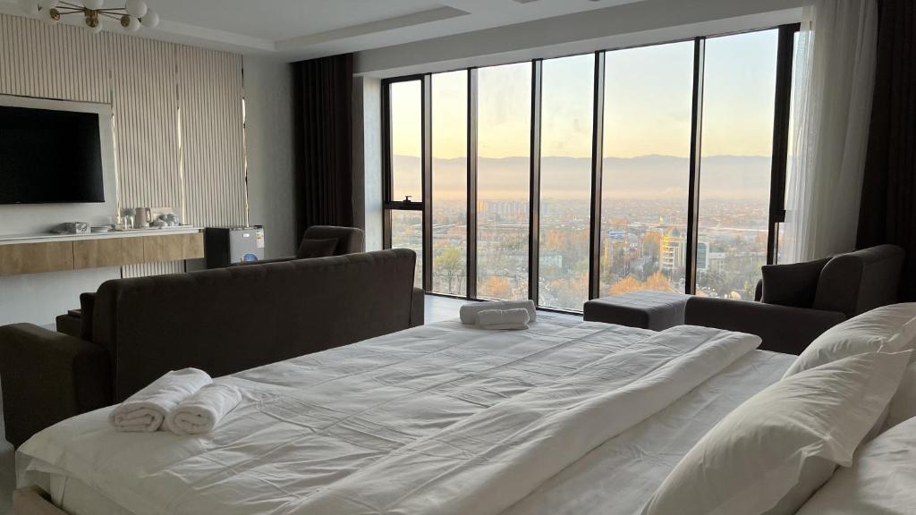 ein großes Bett in einem Zimmer mit einem großen Fenster in der Unterkunft Firdavsi Hotel in Duschanbe