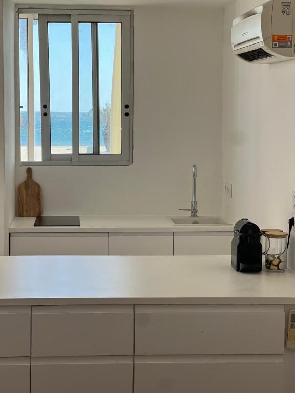 a kitchen with a white counter and a window at Superbe, face à la mer, balneo, rétroprojecteur in Canet-en-Roussillon