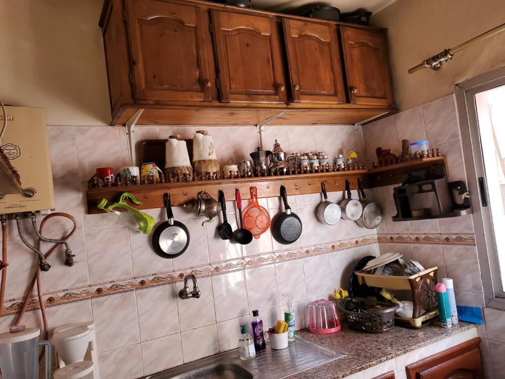 a kitchen with wooden cabinets and utensils on the wall at Appartement entier de 4 pièces à 10 minutes de morroco mall in Casablanca