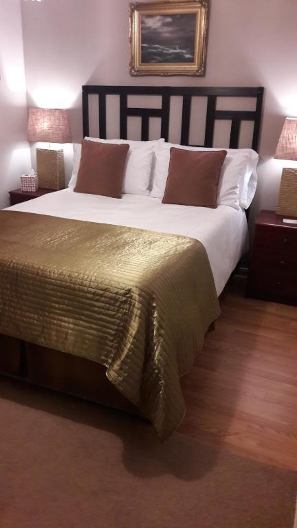 una camera da letto con un grande letto con lenzuola bianche e cuscini marroni di No.9 a Tettenhall
