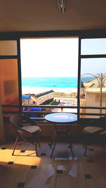 Zimmer mit Tisch und Stühlen und Strandblick in der Unterkunft شاليه في المعموره in Alexandria