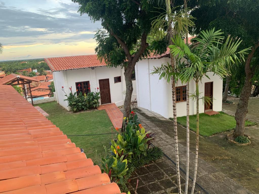 Una casa blanca con un árbol delante. en Morro Branco Suítes - Hospedaria Morro Branco, en Beberibe