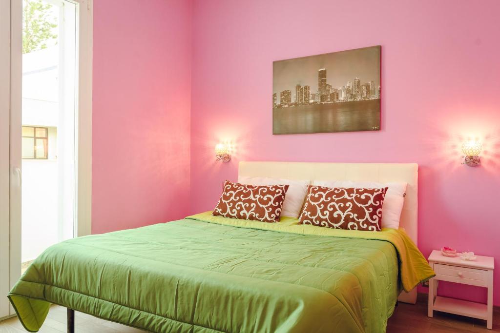 Un dormitorio con paredes rosas y una cama verde. en PINK BARBIE'S HOUSE, Domus Lumeras, en Alghero