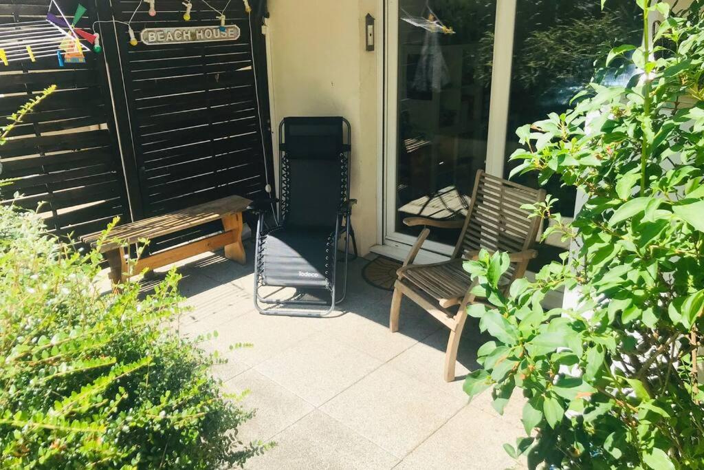 2 chaises assises sur la terrasse couverte d'une maison dans l'établissement Appartement jardin privatif, à Asnières-sur-Seine