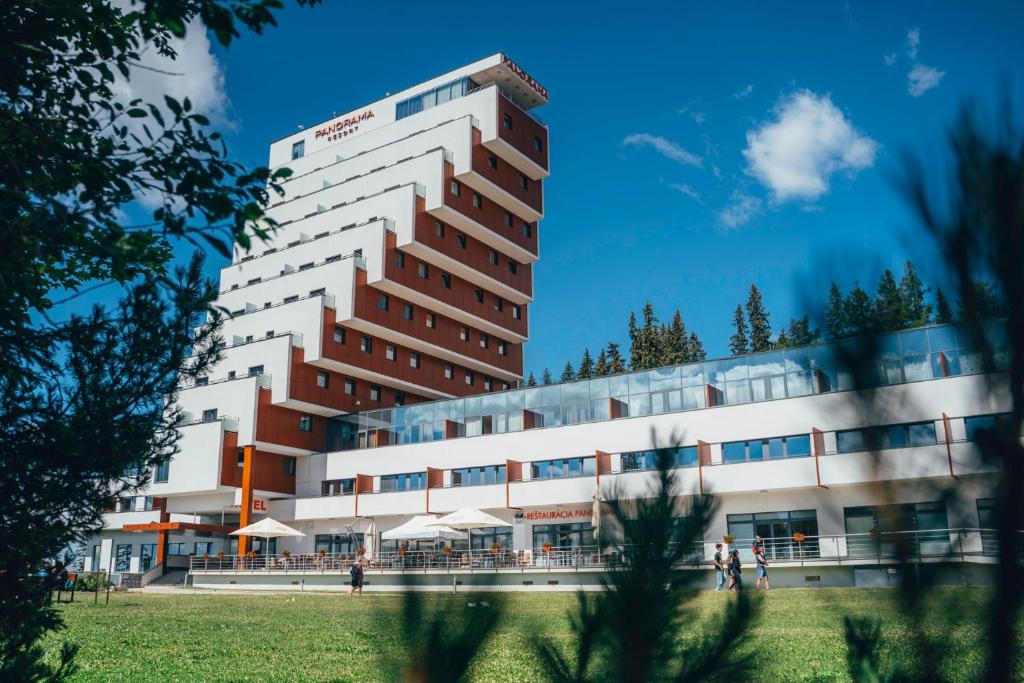 un grand bâtiment avec des personnes debout devant lui dans l'établissement Hotel Panorama Resort, à Štrbské Pleso