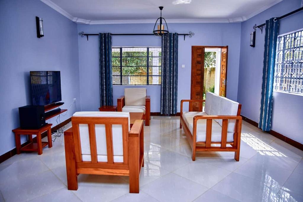- un salon avec des chaises, une table et une télévision dans l'établissement Millance volunteer hosting and safaris, à Arusha