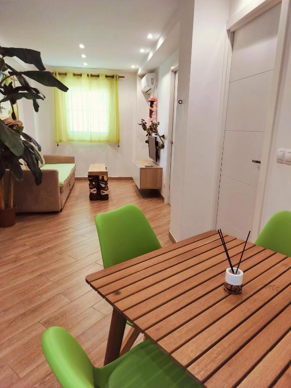 salon z drewnianym stołem i zielonymi krzesłami w obiekcie Wonder Nerja Paraiso Apartamento w mieście Nerja