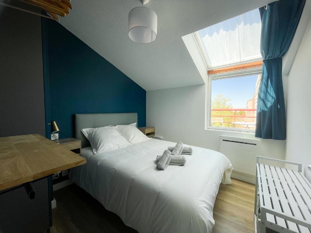 une chambre avec un grand lit blanc avec une fenêtre dans l'établissement Perle Bleu - Ravissant Logement Toulousain, à Toulouse