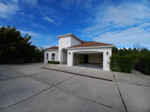 a white building with a garage on a driveway at Kolibri Central Villa in The Bight Settlements