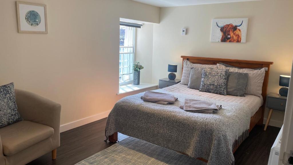 a bedroom with a bed and a chair and a window at City Centre Bridge Street Apartment in Kirkwall