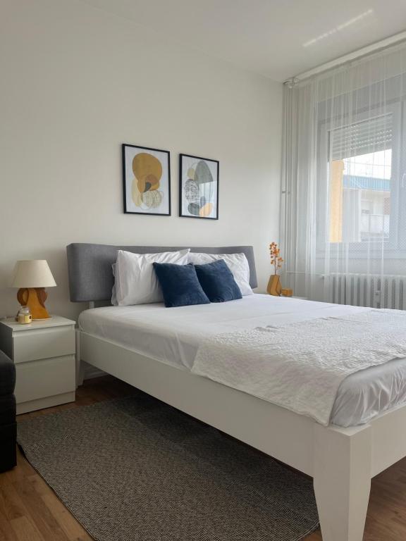 a white bed with blue pillows in a bedroom at Danube Sunrise in Kladovo