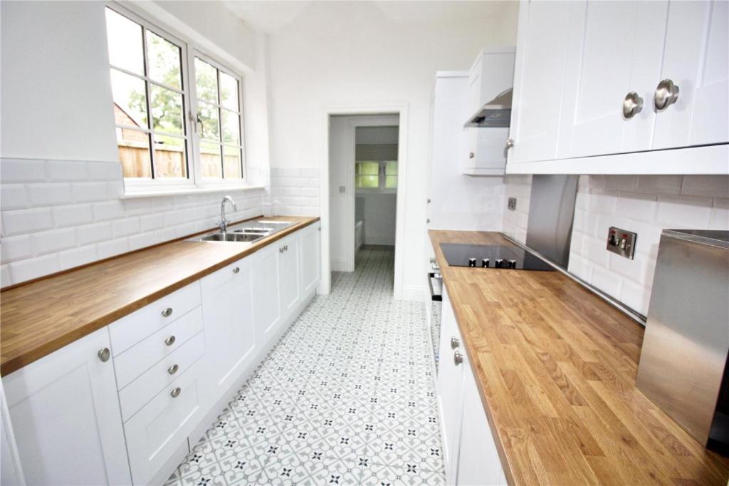 una cocina con armarios blancos y encimeras de madera en Exceptionally Stunning Four Bed Terraced House With Two Bathrooms- Recently Renovated en Spon End