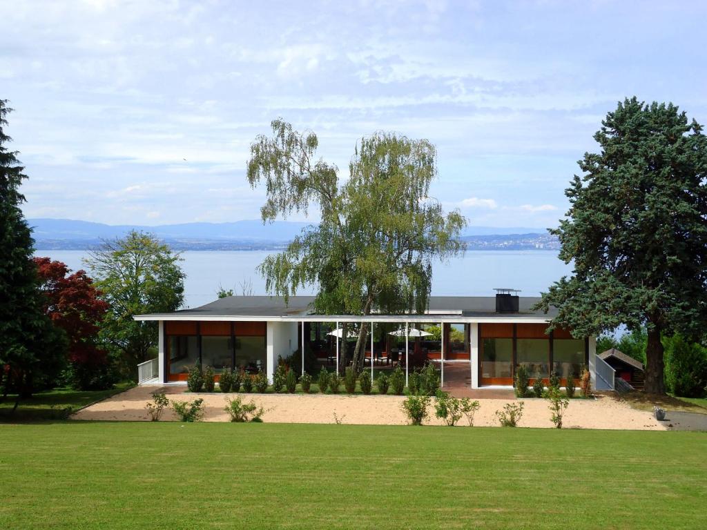 ein Haus mit Blick auf das Wasser in der Unterkunft Villa with Lake Geneva views; 1960 (mid century modern) style in Neuvecelle