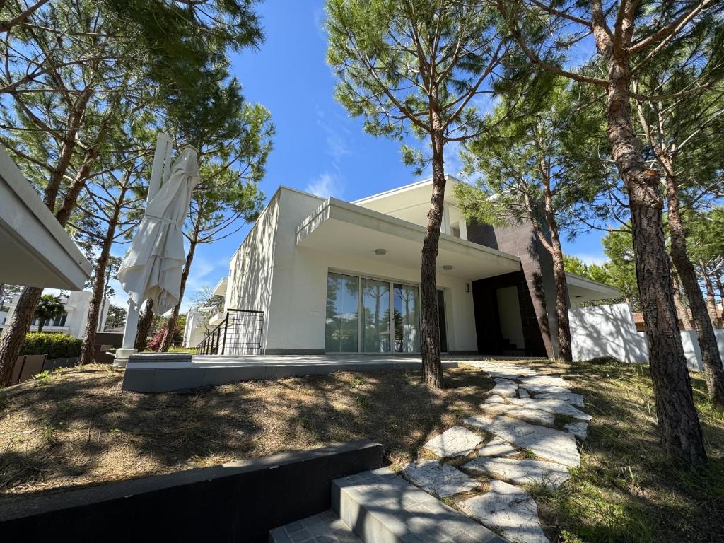 a white house with trees in front of it at Villa Sunshine in Lignano Sabbiadoro